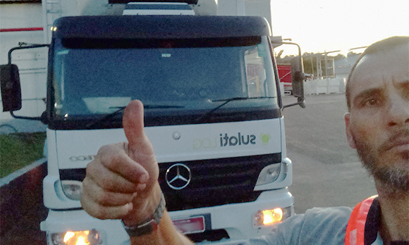 Fotografia de um homem fazendo sinal de positivo com o polegar, em frente ao seu caminhão branco. - Nova operação da Sulati facilita transporte entre as indústrias da Minuano